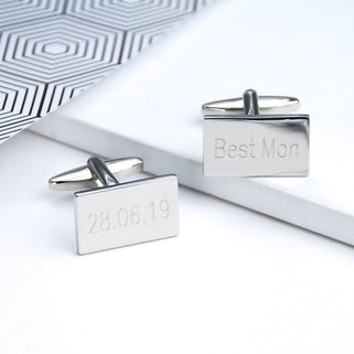 Silver rectangle cufflinks with "28.06.19" and "Best Man"  engraved on them shown in close up shot.