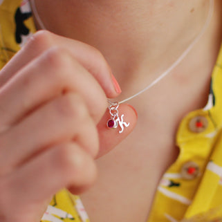 Sterling Silver Script Mini Initial "K"  Letter Necklace with July/Ruby Birthstone shown in close up shot on model