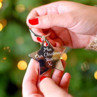 Christmas Star Keyring with Personalised message "Mia Our Christmas star x" engraved on the front shown in close up shot of model holding keyring 