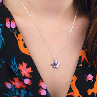 Silver Star with "M" Engraved and Blue Topaz/December birthstone charm Necklace shown close up on model