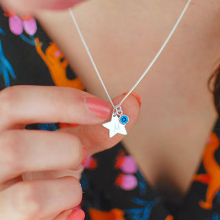 Silver Star with "M" Engraved and Blue Topaz/December birthstone charm Necklace shown close up on model
