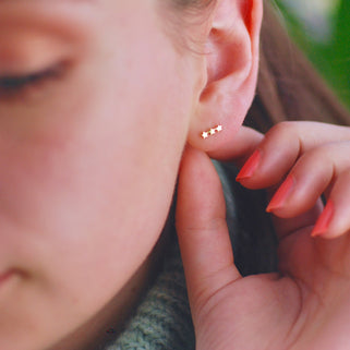 Gold vermeil tiny trio star climber earrings shown in close up shot on model