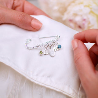  Sterling Silver Wedding Keepsake Charm Pin with August/Peridot birthstone, script letter "A" initial, engraved oval disc "21.4.22",  script letter "M" initial and March/Aquamarine birthstone shown in close up shot