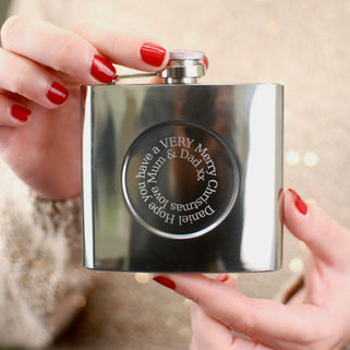 Silver hip flask with engraved spiral message on the front shown in close up shot with model.
